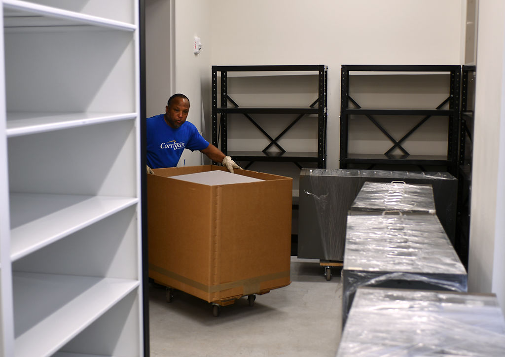 Jesse Randleman rolls a box of microfilm and old newspaper into the new storage area
